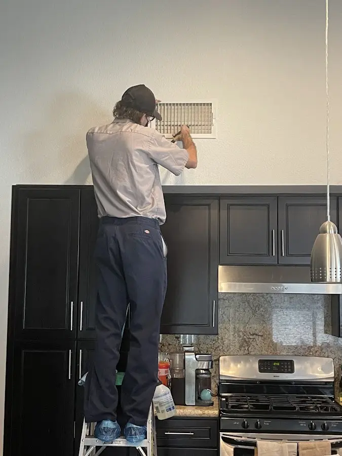 Technician inspecting an air vent during HVAC service in Fergus Falls